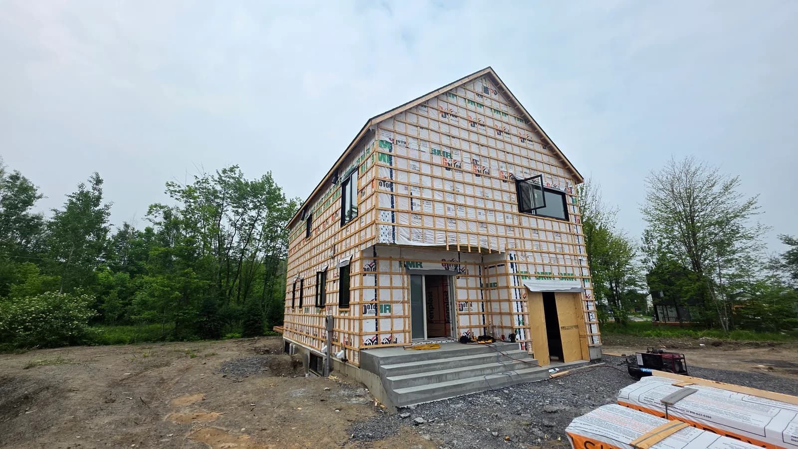 Maison neuve en construction, membrane pare-air et escalier de béton